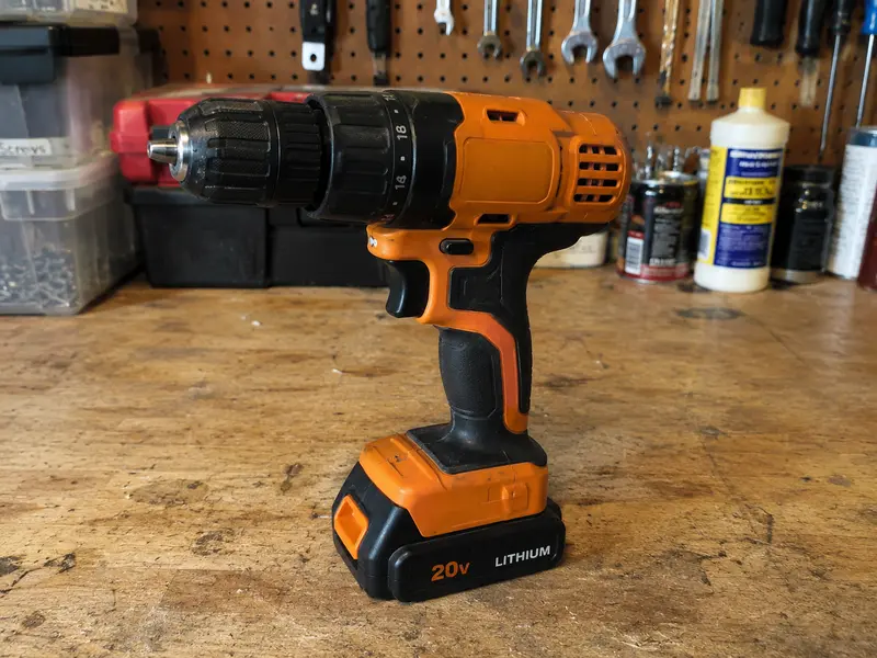 Orange cordless drill standing on a workbench